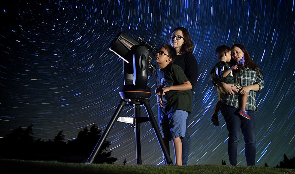 Family outside using telescope looking at stars