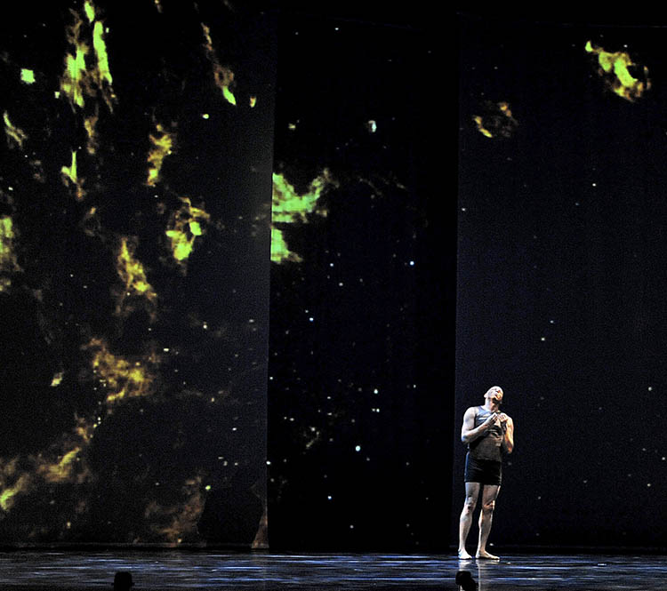 Dancer on stage with isotopes in background