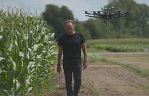 Bruno Basso walking next to corn field with a drone