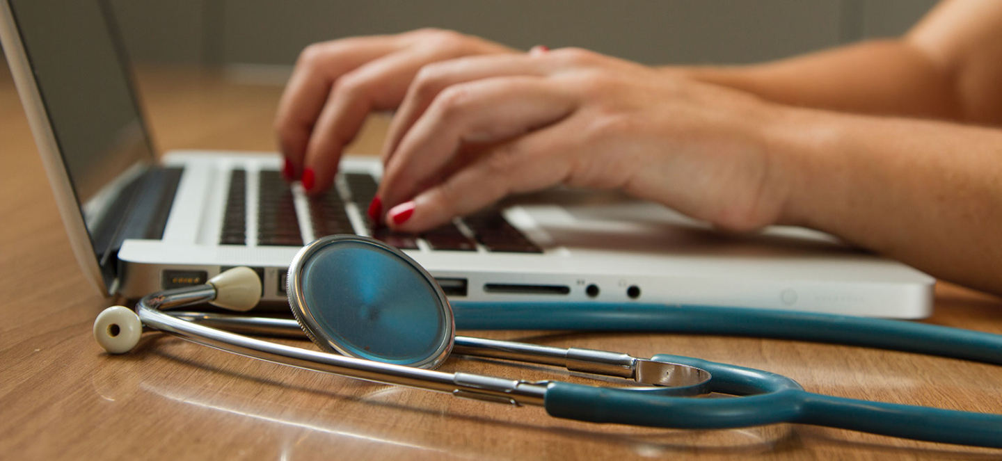 stehoscope and hands typing on a laptop