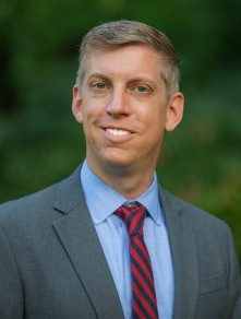 Portrait photo of Justin Kirkpatrick, man with fair completion, light hair in suit and tie