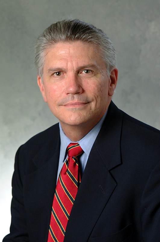 Portrait of JR Haywood. Man with greying hair in suit and tie