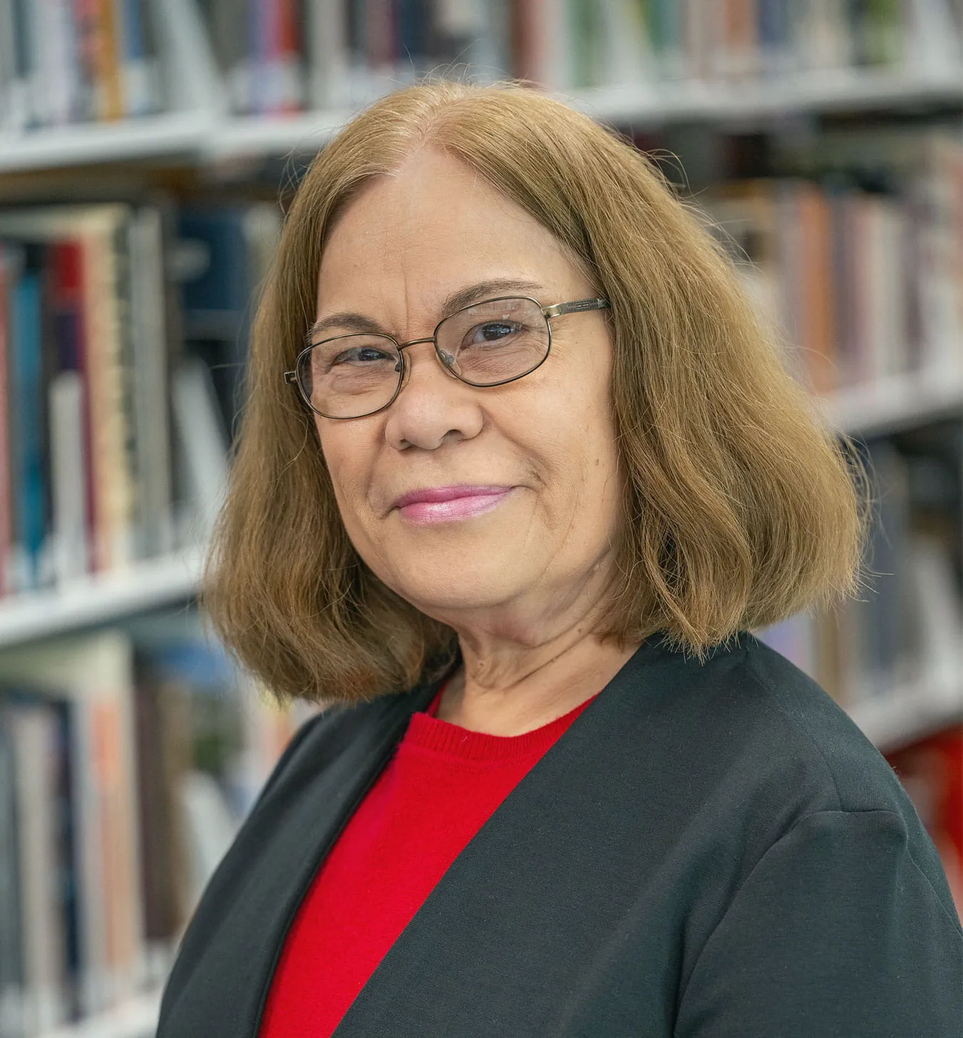 Evangelyn Alocilja posing for a portrait photo in front of a bookcase.