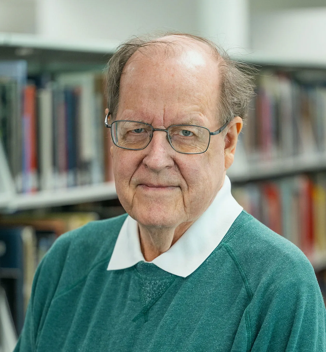 James Fairweather posing for a portrait photo in front of a bookcase.