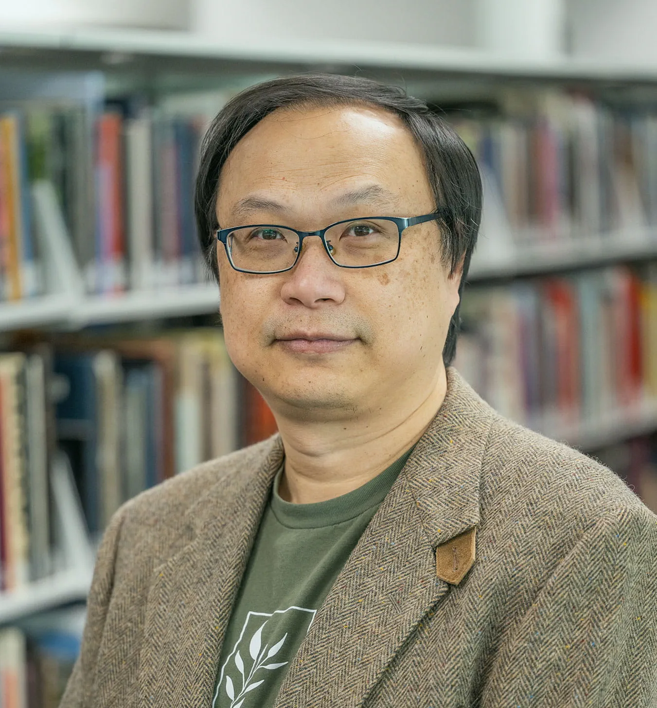 Shin-Han Shu posing for a portrait photo in front of a bookcase.