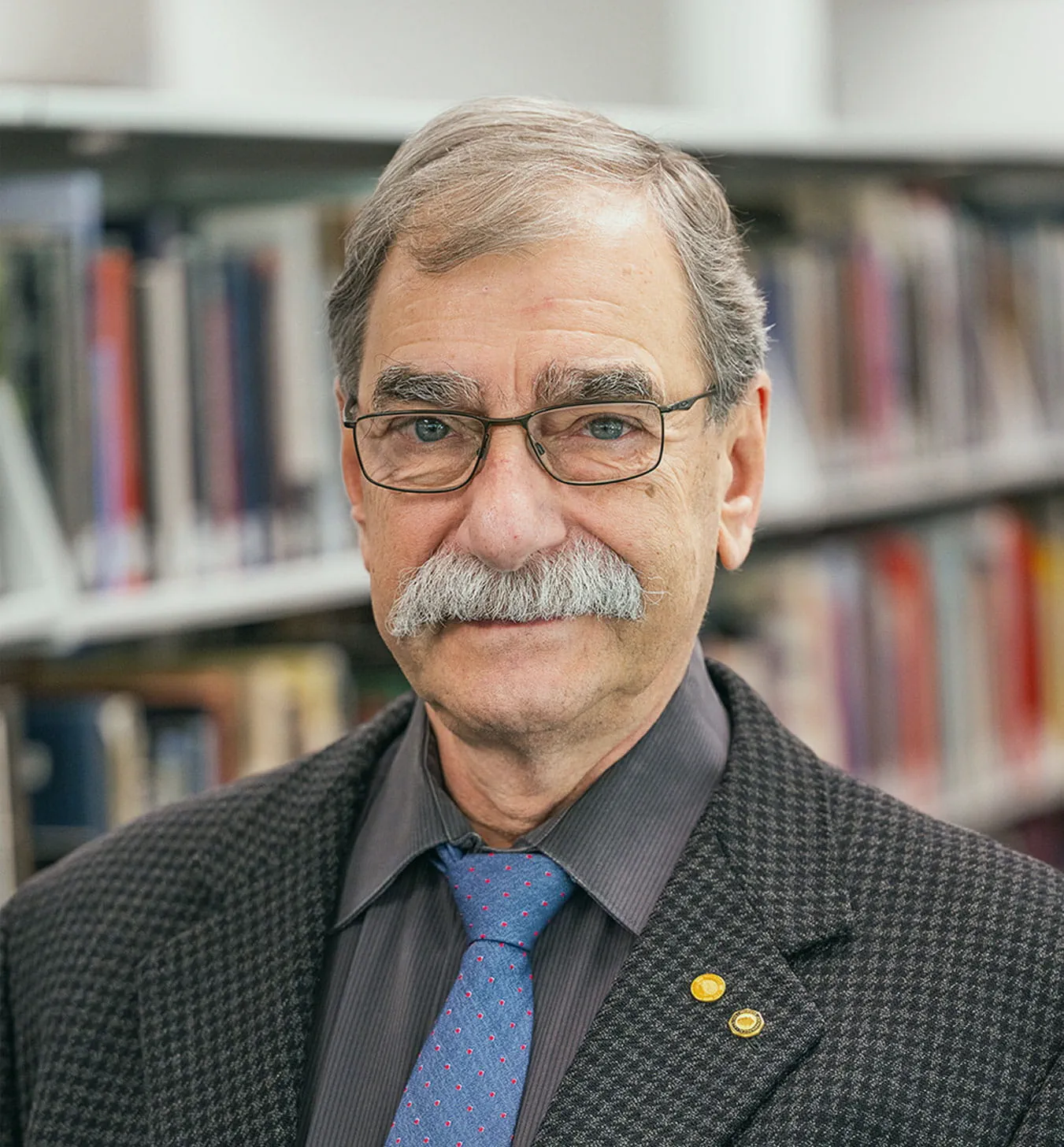 William Lovis posing for a portrait photo in front of a bookcase.