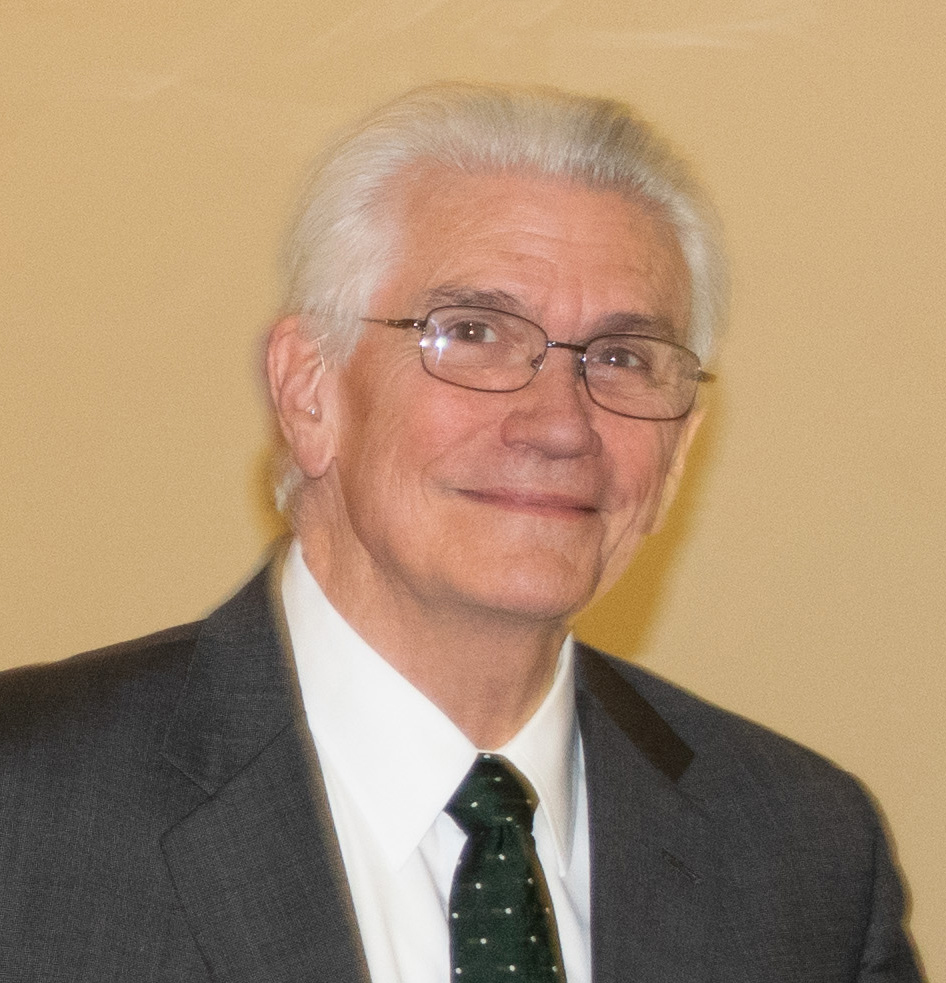 J.R. Haywood, a caucasian man with white hair and glasses wearing a dark suit