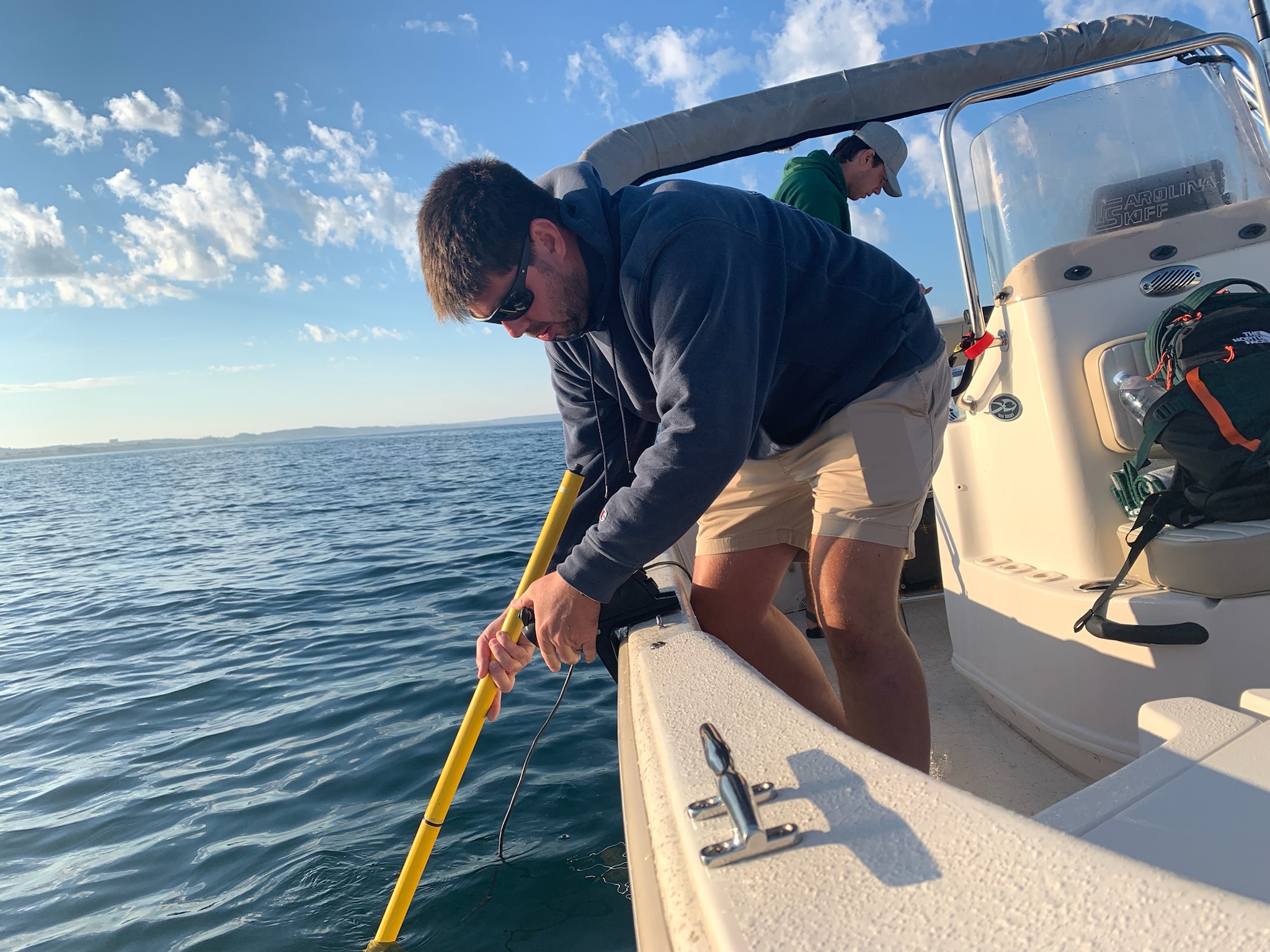 A man using a measuring instrument off the side of a boat