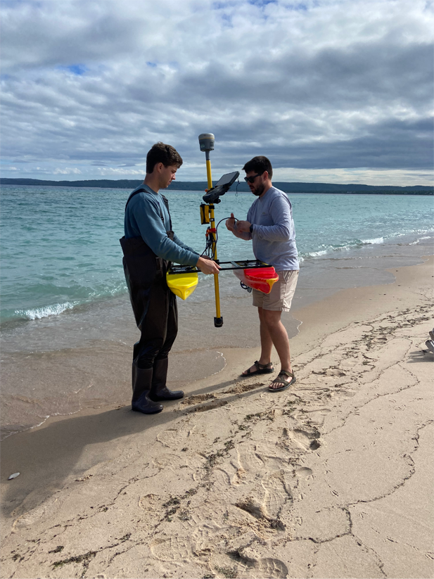 Two people standing on a beach with scientific measuring equipment