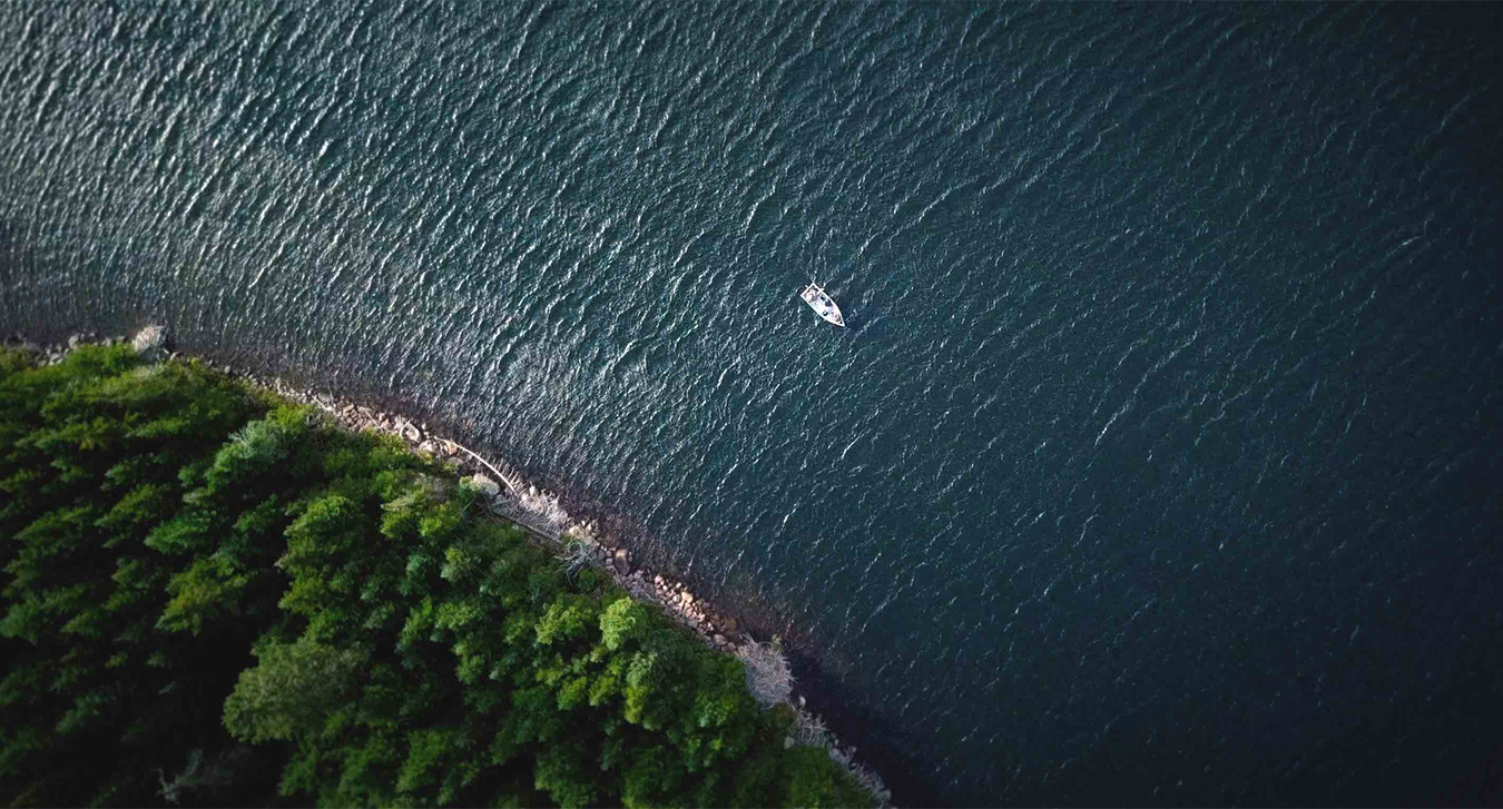 A boat driving down a coastline as seen from above