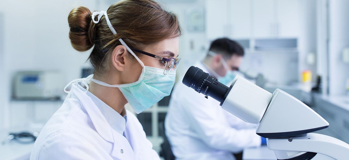 A woman looking into a microscope