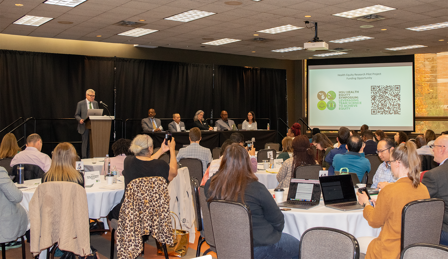 A speaker and panel at a symposium. 