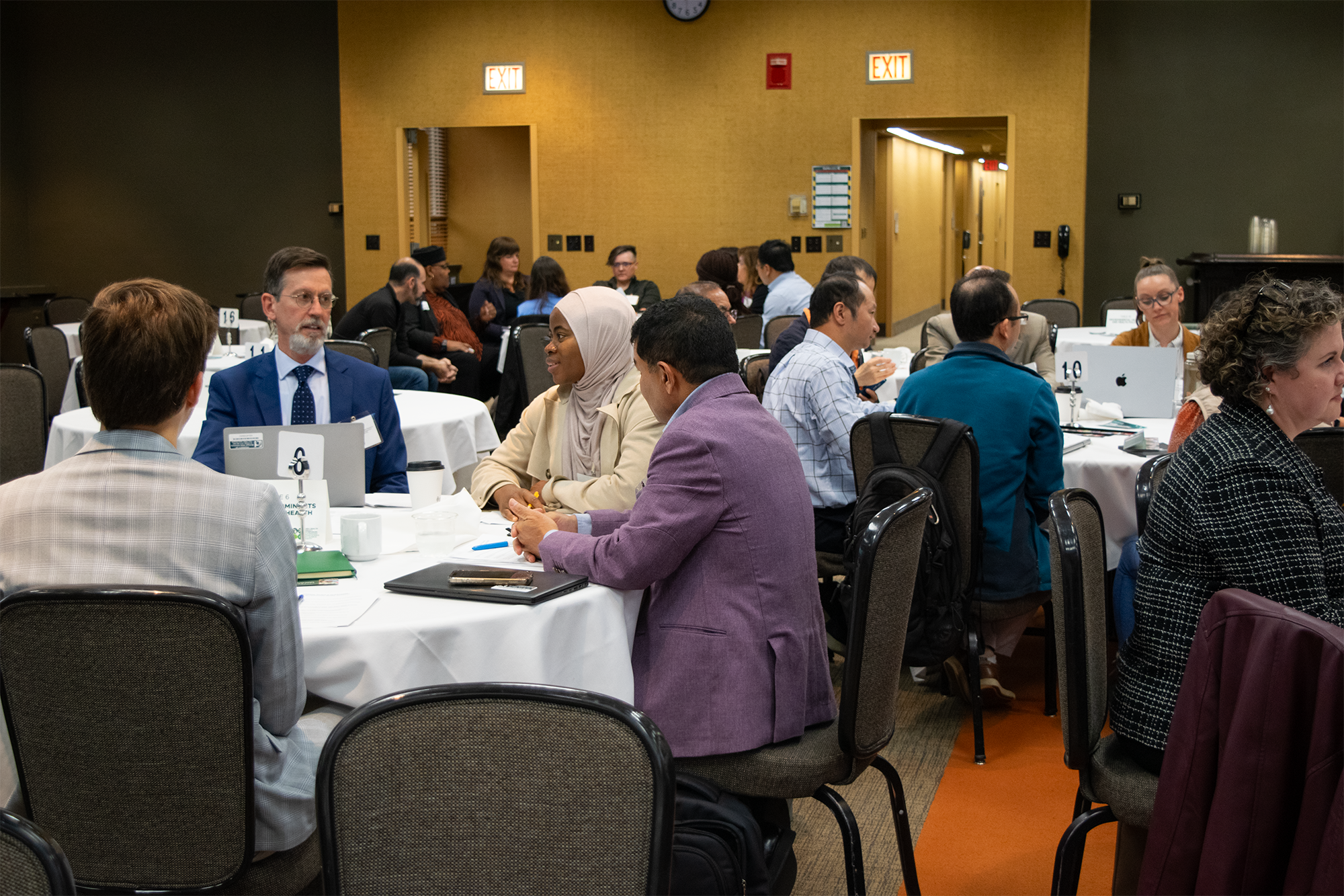 People at working tables during a symposium. 