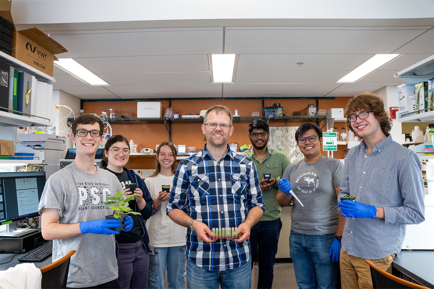 A group of people in a lab holding up plants and samples