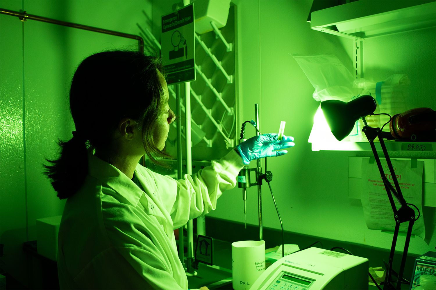 A researcher holding up a vial in a room with green lights