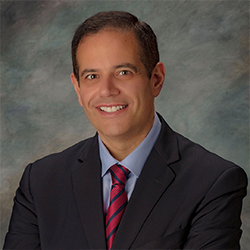 Steven Kalkanis Wearing a Suit Posing for a Headshot