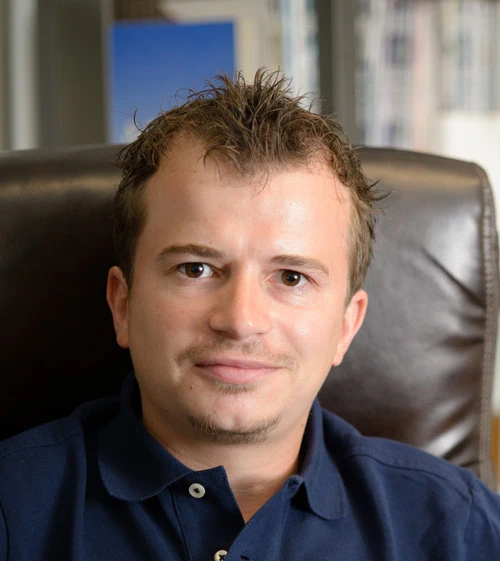 A headshot of Alexander Johnson wearing a navy polo