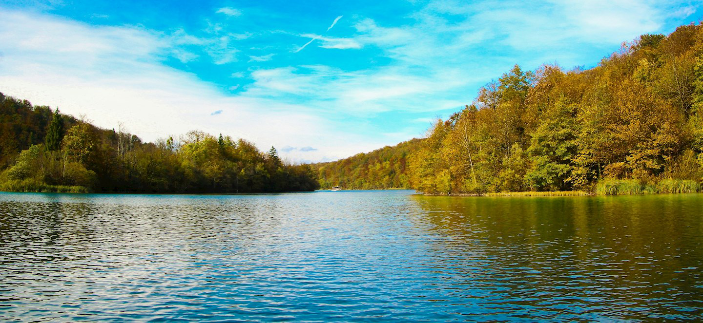 A lake surrounded by trees in fall on a sunny day