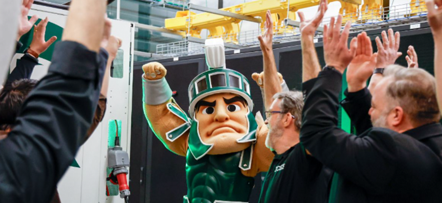 MSU's mascot, Sparty, raising hands with a crowd