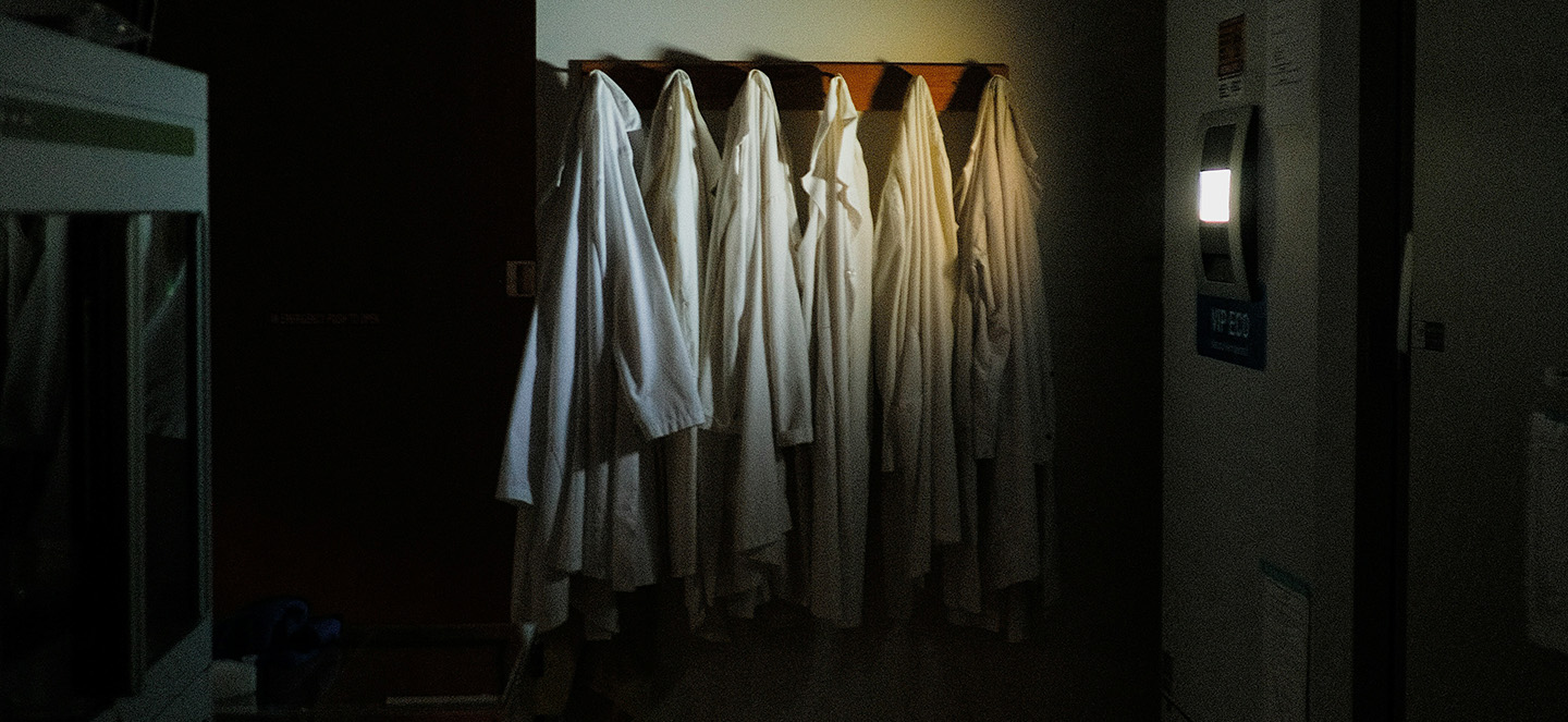 A dark empty lab with several lab coats hanging