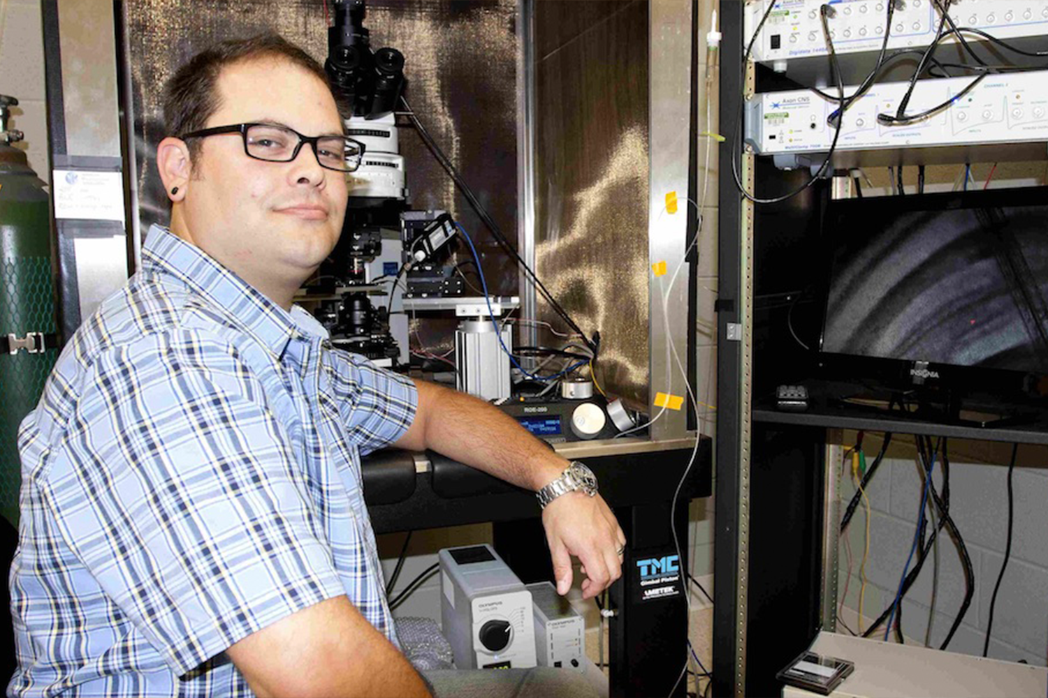 A person leaning on a desk next to research equipment