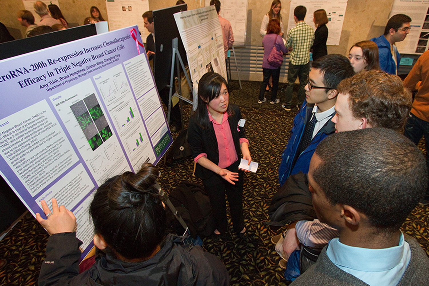 A student giving a research poster presentation to a group at the MSU Union