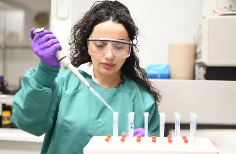 Woman doing pipette process in a lab wearning green scrubs