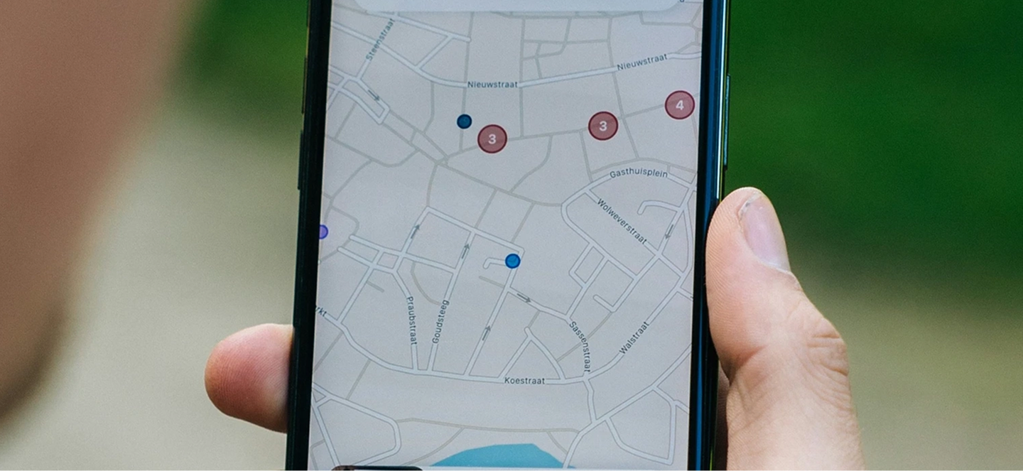 A hand holds a smartphone displaying a digital map and location markers