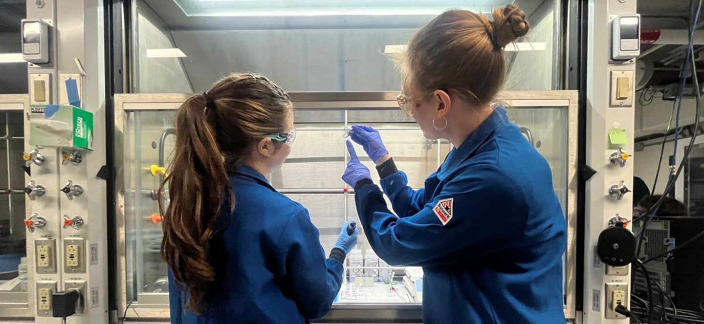 Two women using a machine at the FRIB