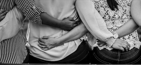 Black and white image of women from the back having their arms behind their back. 