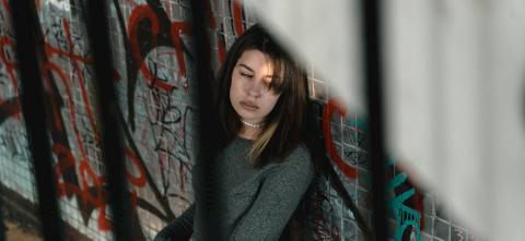 Women sitting against a wall with graffiti.  