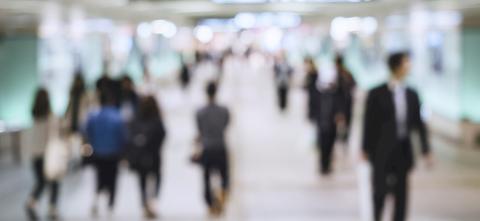 Blurred image of a group of people walking through a hall.