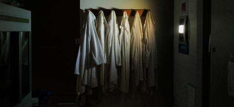 A dark empty lab with several lab coats hanging