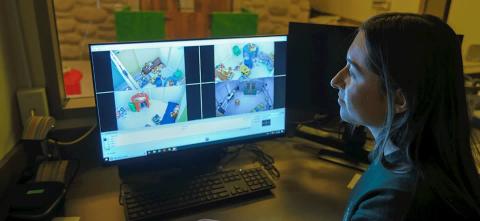 A person watches video feeds of toy filled playrooms on a computer screen