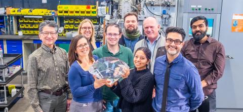 Research lab group holding large diamond 