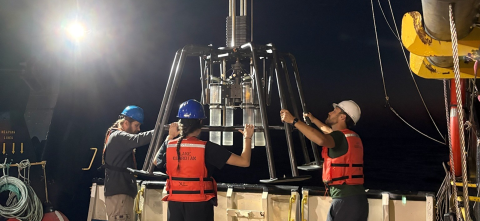 Three members from the Hardisty team gathered around a submersible metal cage with four plastic collection tubes