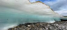 A sheet of ice frozen over rocks on a shoreline