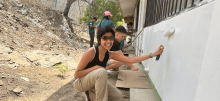 Veona Cutinho smiling while helping to painting building