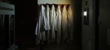 A dark empty lab with several lab coats hanging