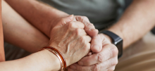 Hands of two people clasped together in a caring gesture